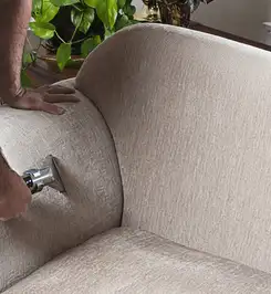Professional upholstery cleaner deep-cleaning a fabric sofa with a handheld extraction tool and hose Tallahassee, FL.